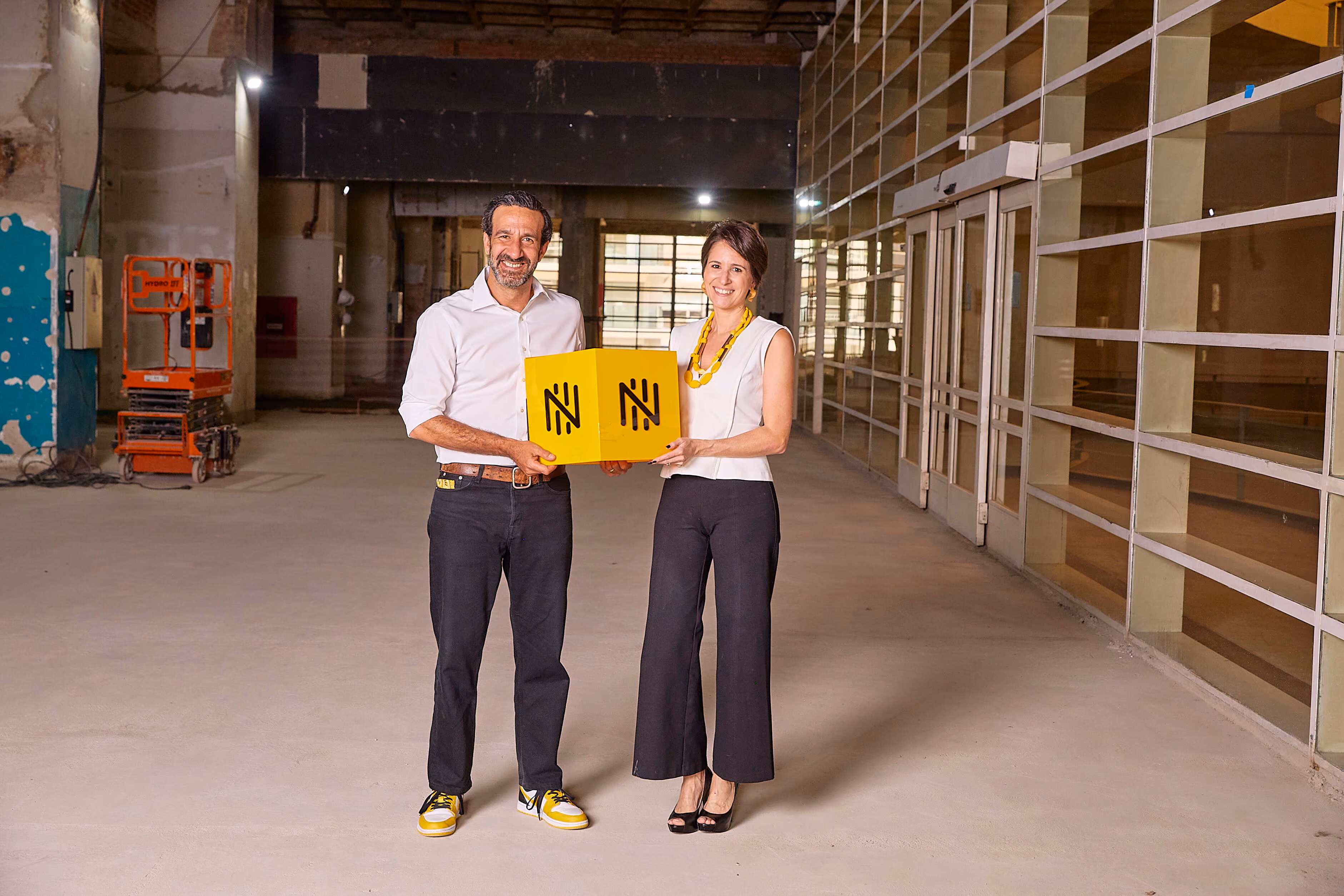 Executivos da Nomad seguram o cubo amarelo da marca no futuro espaço do Time Out Market São Paulo
