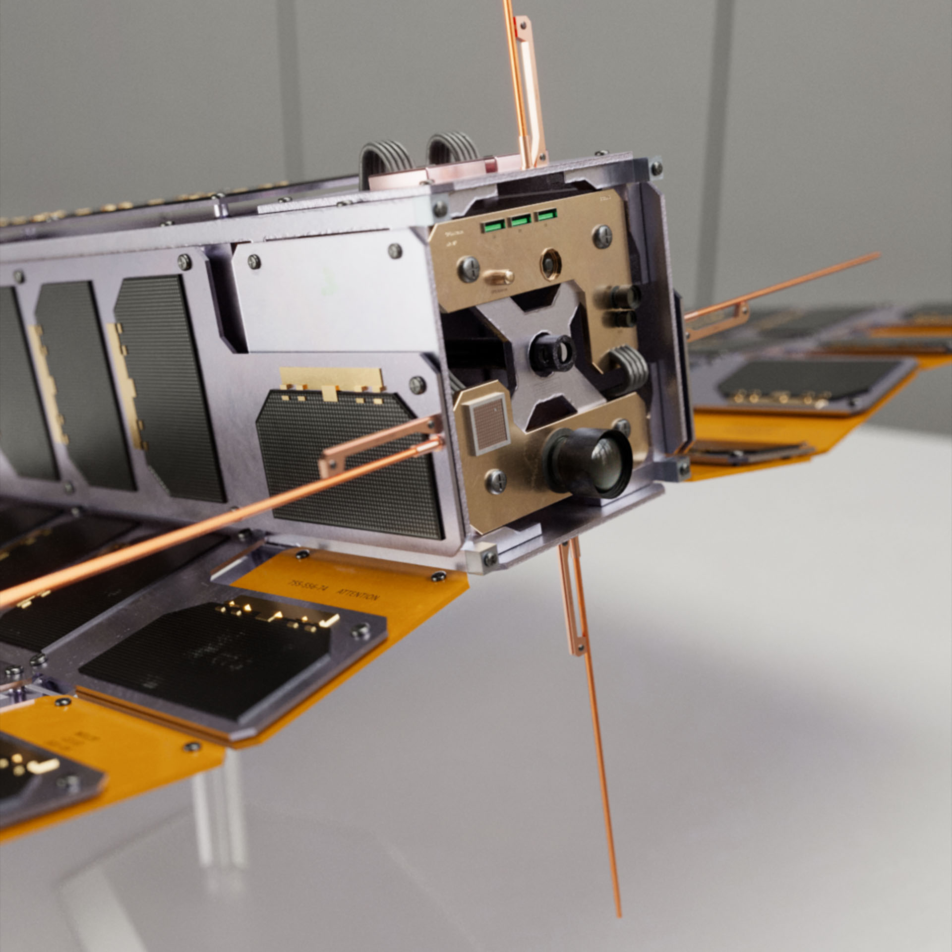 A military CubeSat made of metallic parts and small solar cells featuring a camera lens and a barrel coming out from the middle. This is the Deli Platter CubeSat from Operation: Deli Platter.