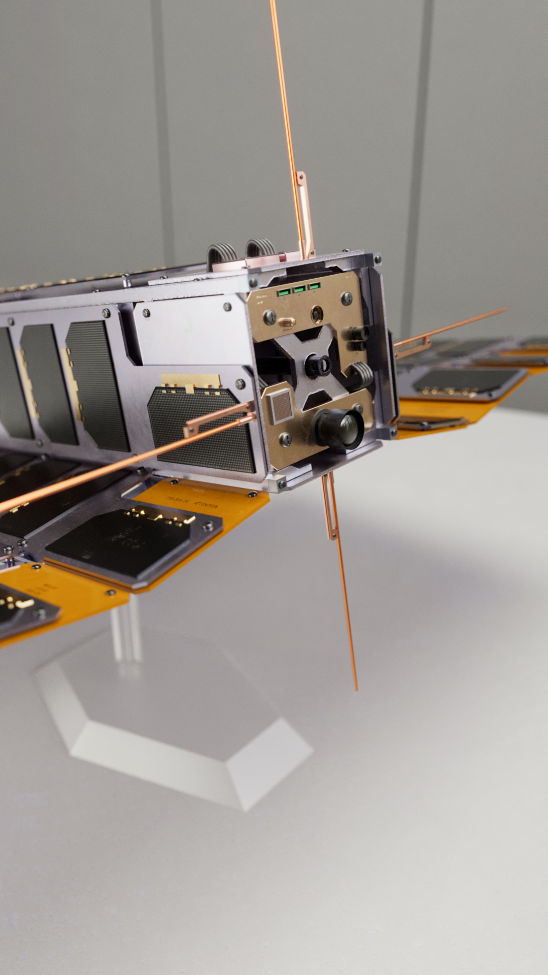 A military CubeSat made of metallic parts and small solar cells featuring a camera lens and a barrel coming out from the middle. This is the Deli Platter CubeSat from Operation: Deli Platter.