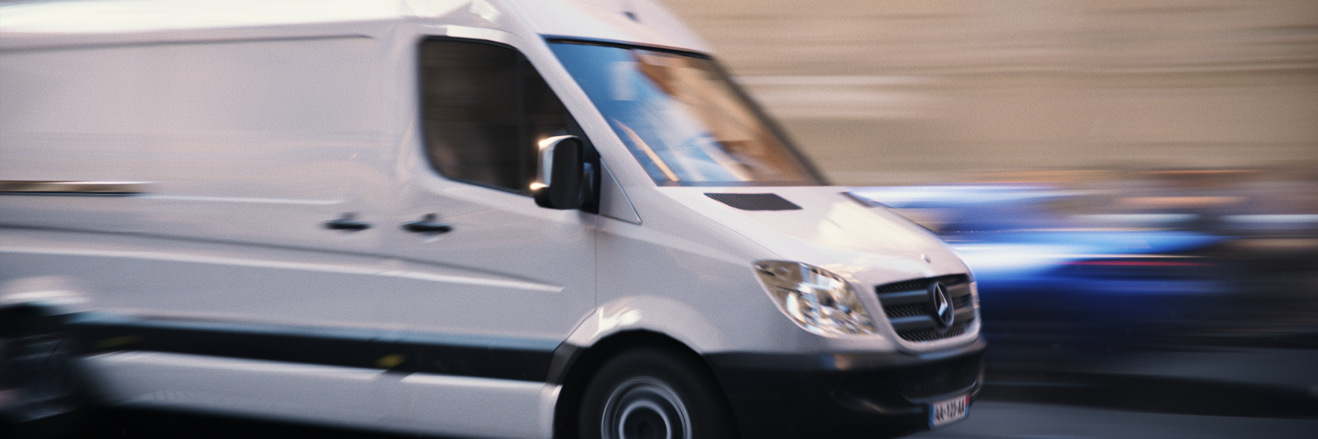 A white Mercedes Sprinter van speeding in motion-blur through the streets of Europa in Heist Club.