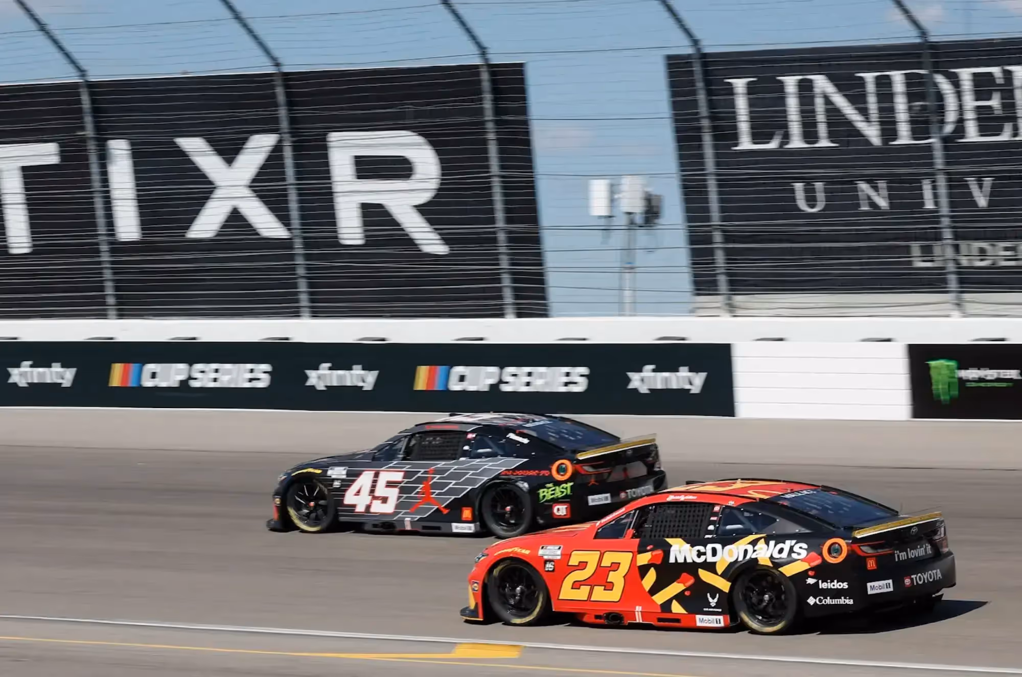 Side view of cars and Steve Lauletta racing down track
