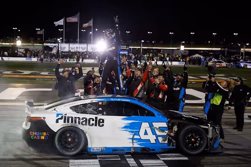 Tyler Reddicks celebrating on top of his car. 