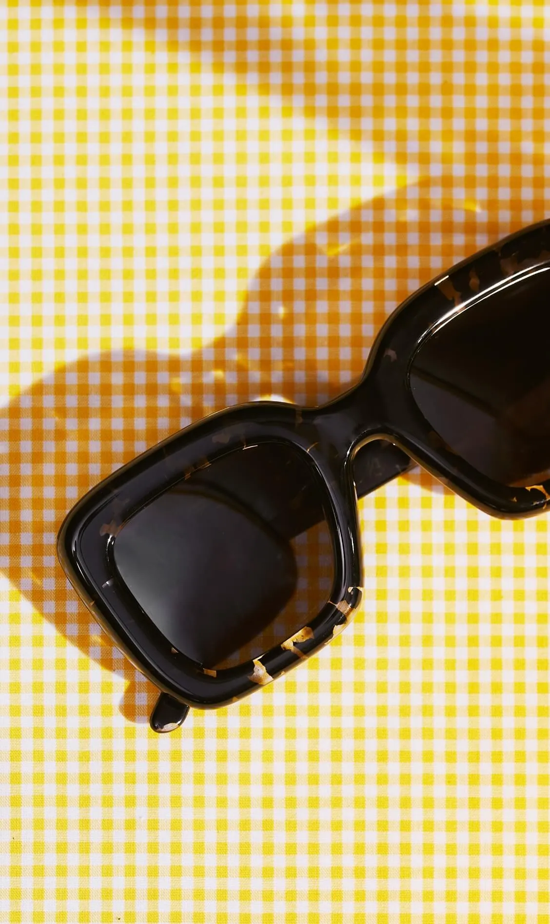 An image of sunglasses on a yellow surface