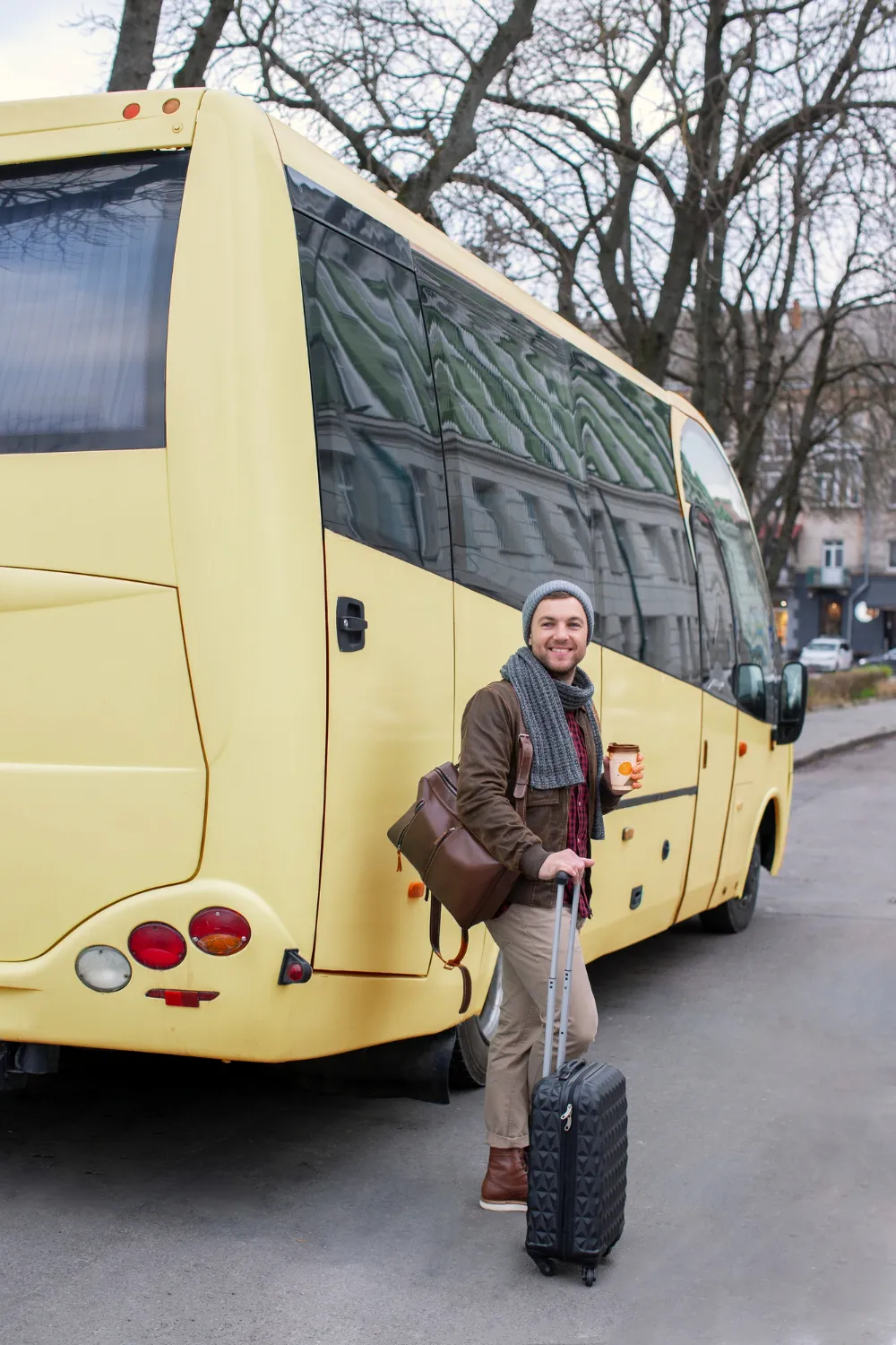 A woman standing next to a yellow bus.