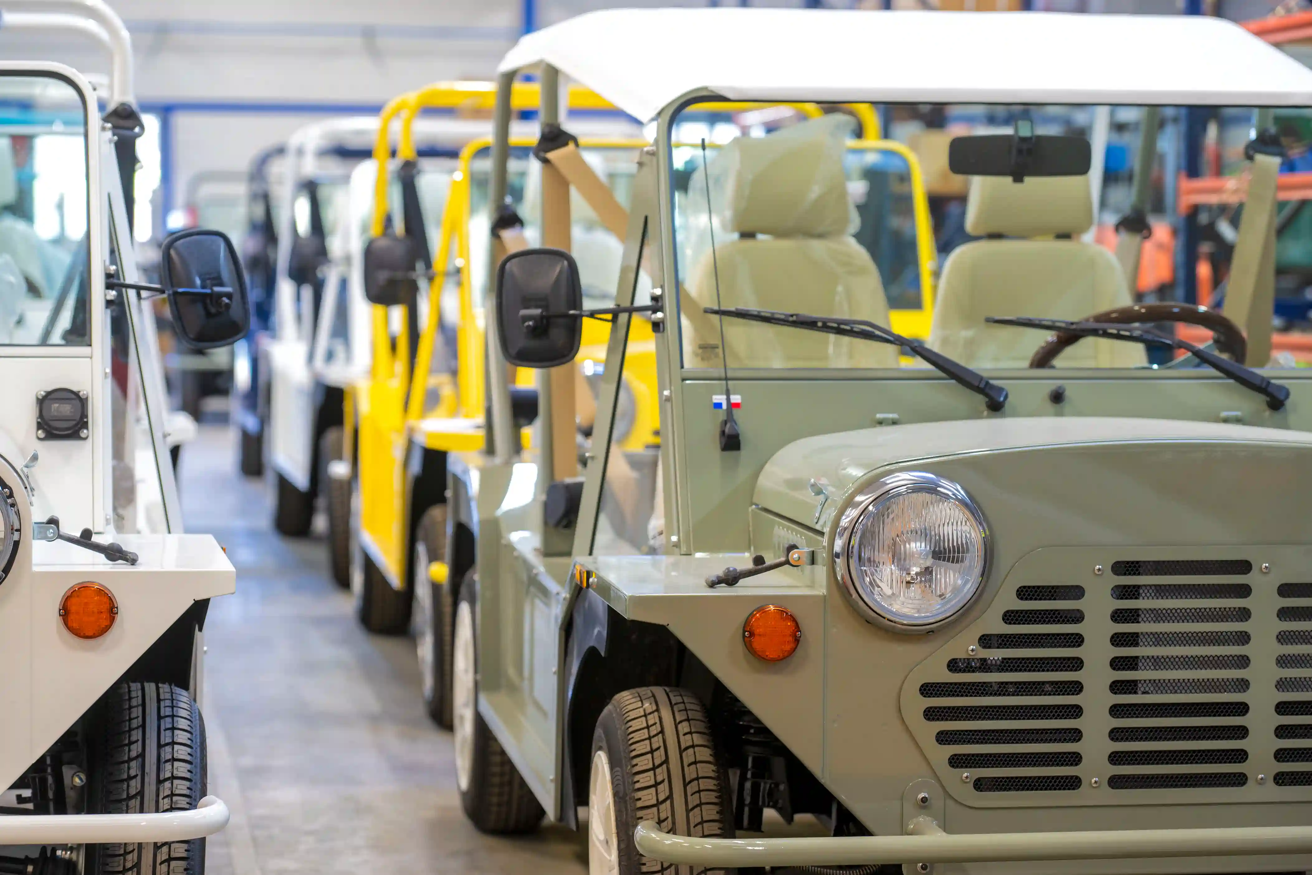 Row of Mini Moke Kate Electric Beach Car in multiple colors lined up inside the factory