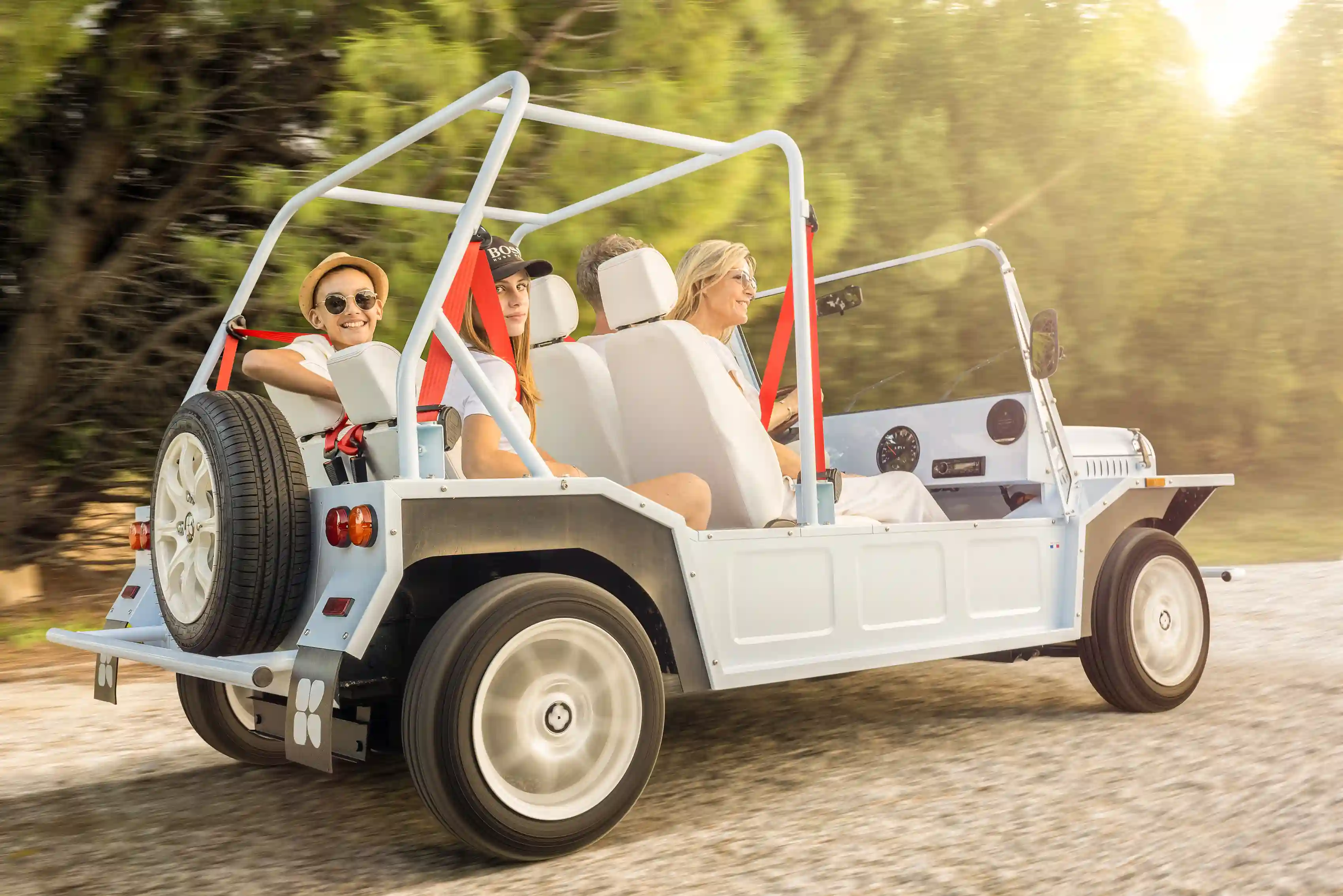 A rich family composed by 1 child, 1 teenager, 1 father 1 mother, on the road at Ibiza Spain in their Kate Mini Moke Electric Beach Car beach buggy type