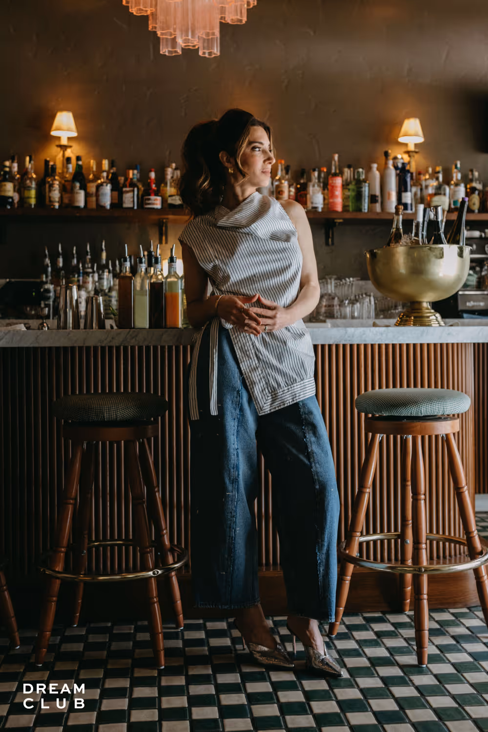 Marie Forleo standing in an upscale bar, looking sophisticated and determined.