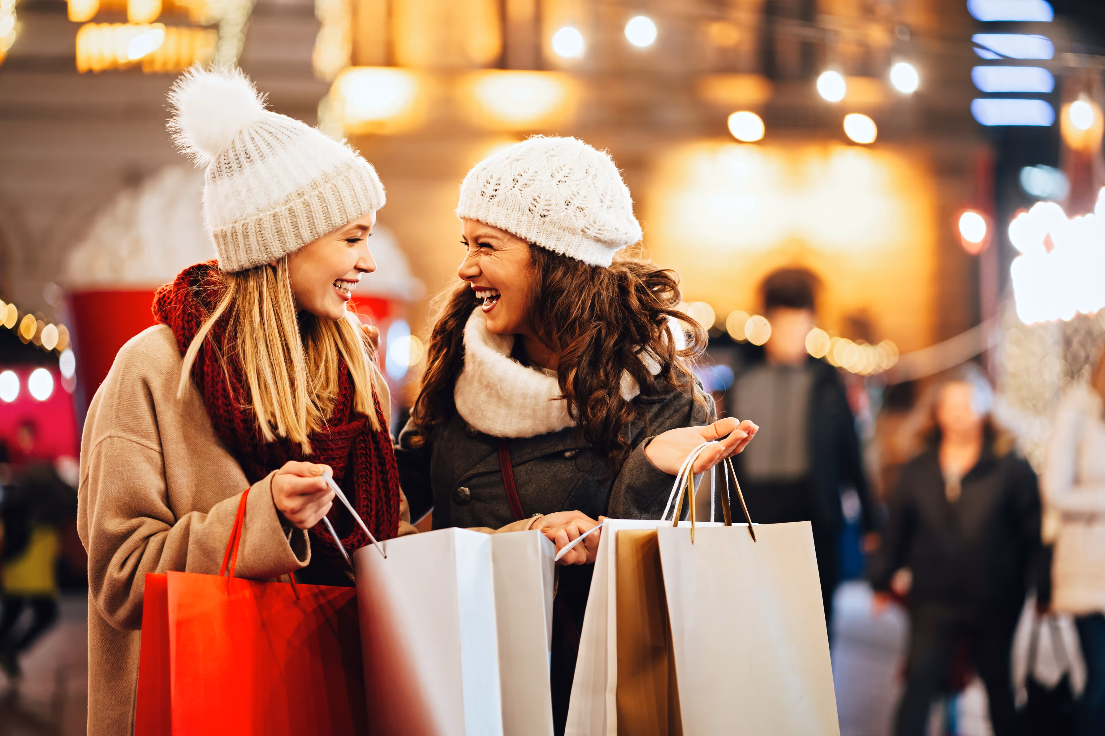 Twee vrolijke vrouwen winkelen samen in een sfeervol verlichte omgeving