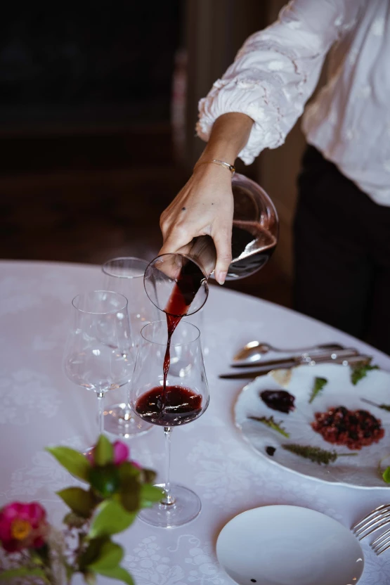 Une table élégamment dressée avec une nappe blanche, des verres, des assiettes, des couverts et un centre de table floral dans une salle décorée chaleureusement.