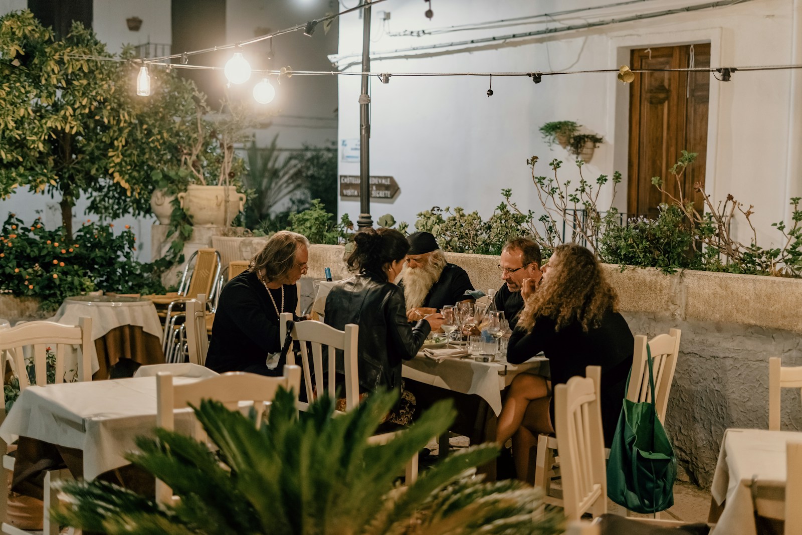 Groupe d'amis dînant en terrasse sur une place lumineuse, illustrant l'expérience client qui va générer des avis répartis sur les différentes plateformes (photo Gabriella Clare Marino via Unsplash)