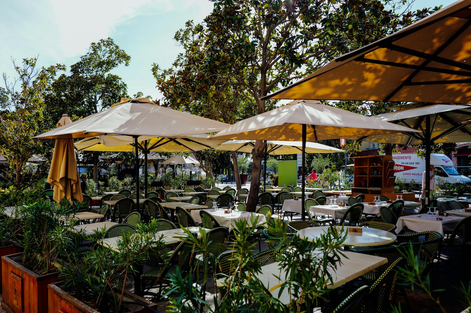 Terrasse de restaurant dressée sous de grands parasols beiges (photo Adrien Olichon via Unsplash)