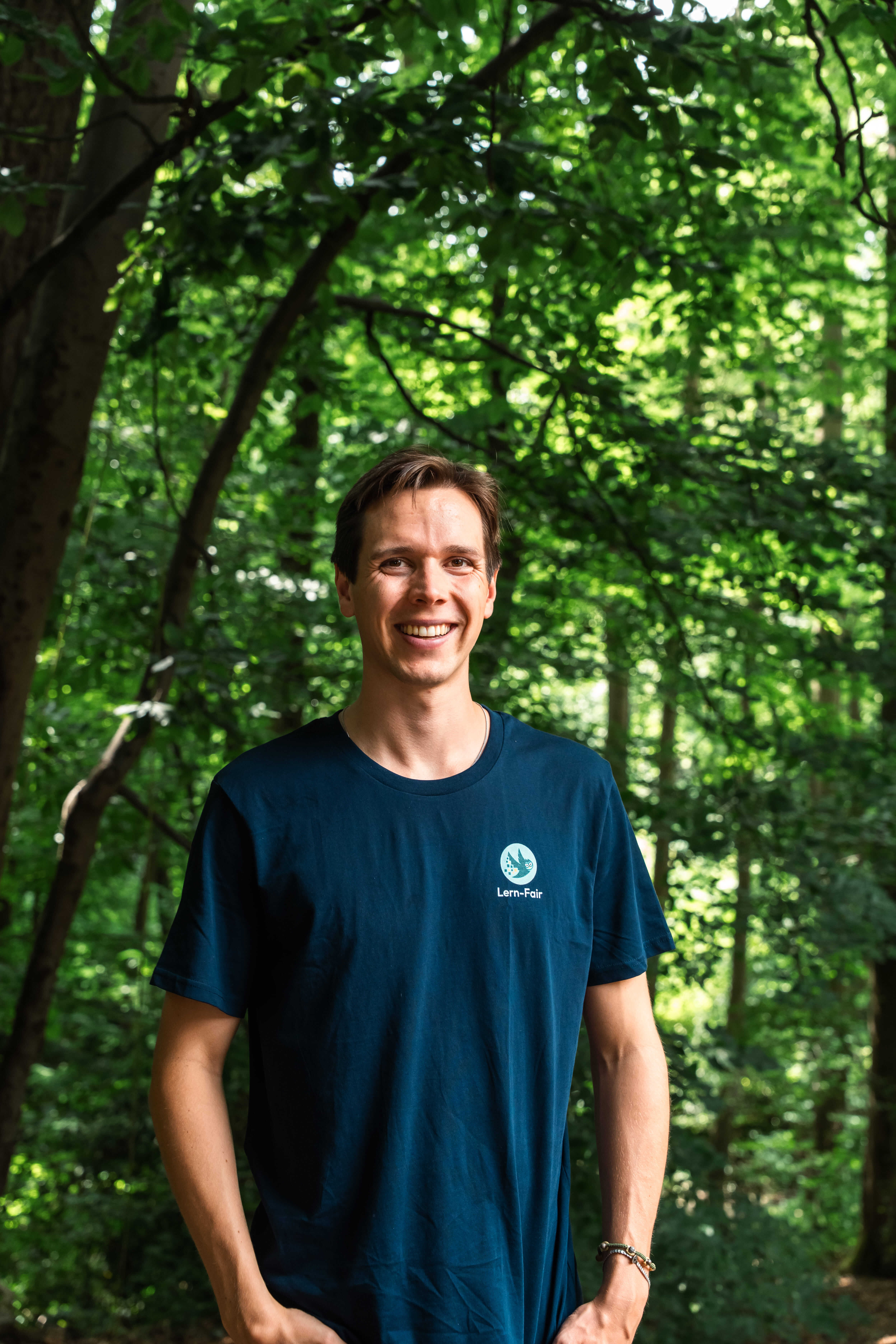 Junger Mann mit Lern-Fair T-Shirt vor Wald