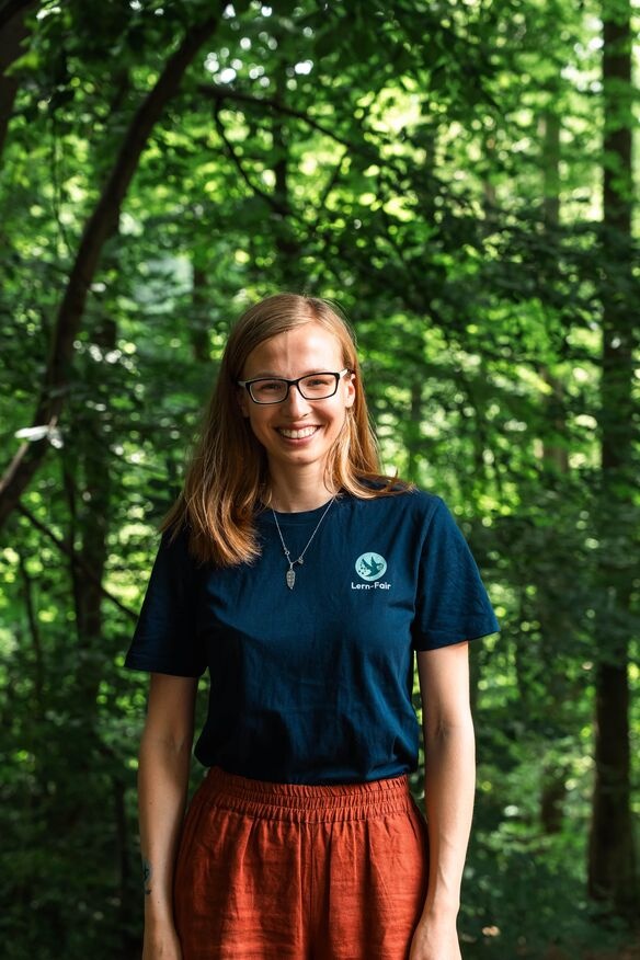 Junge Frau in Lern-Fair T-Shirt vor Wald