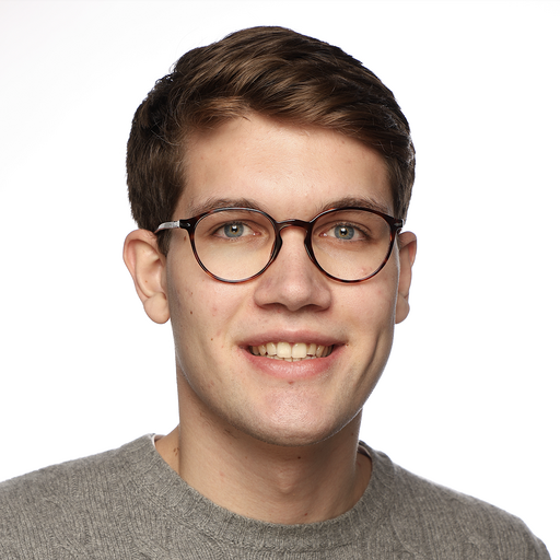 Junger Mann lächelt in die Kamera mit Brille.