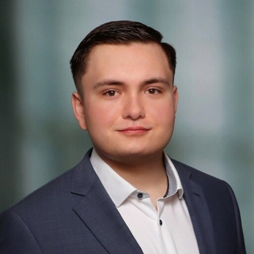 Junger Mann im Anzug schaut selbstbewusst in die Kamera.