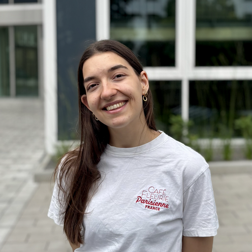 Junge, ehrenamtliche Frau in weißem Tshirt aus dem Lern-Fair Team lächelt in die Kamera.