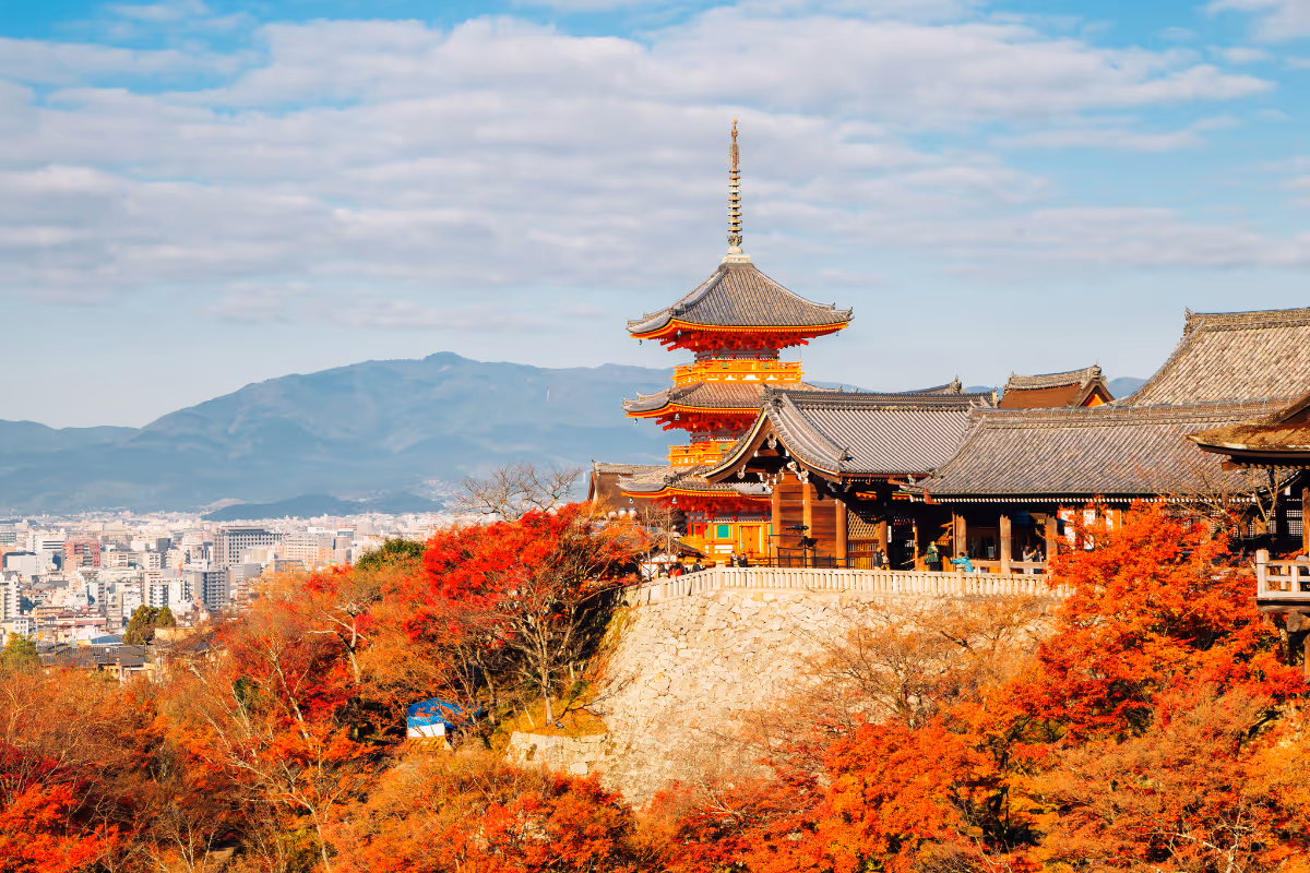 A Japanese temple behind red autumn leaves