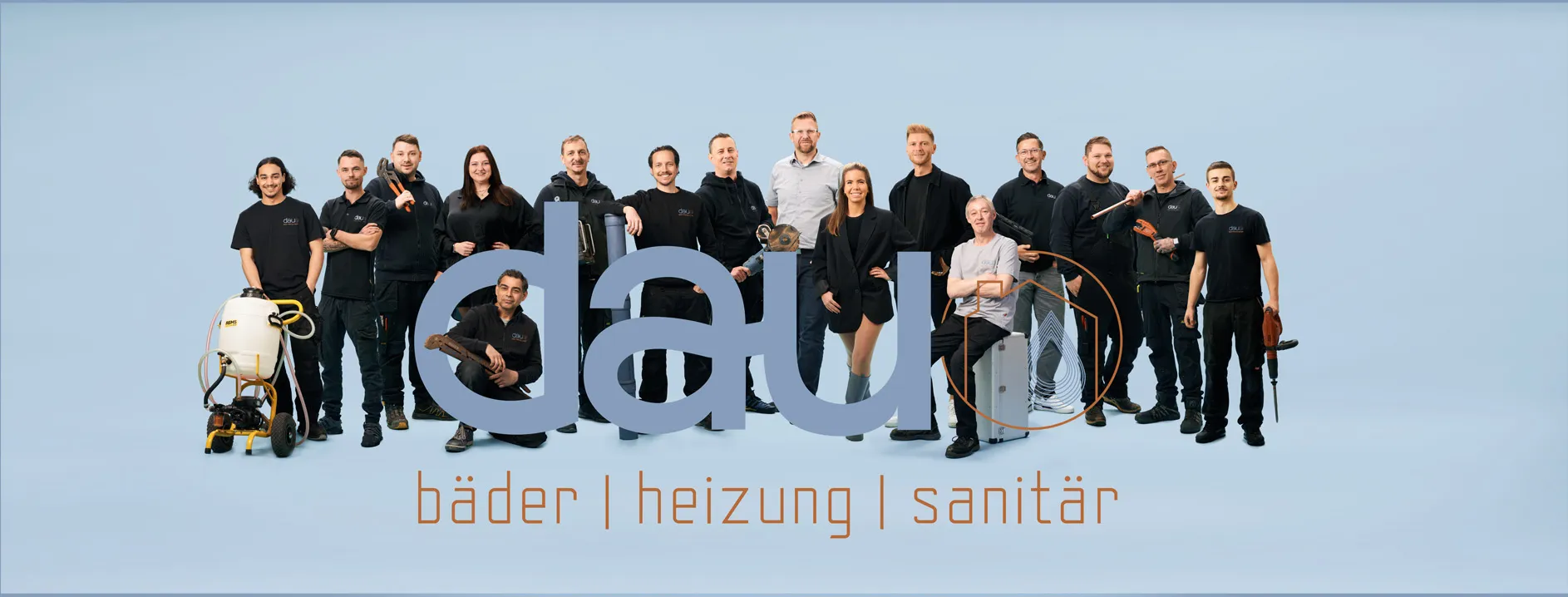 Gruppenfoto eines Teams mit Werkzeugen vor blauem Hintergrund und Schriftzug dau bäder heizung sanitär.