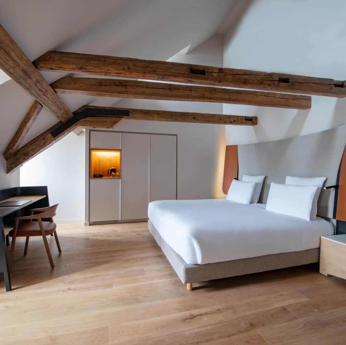 Photo of a hotel room with a large double bed and a small desk