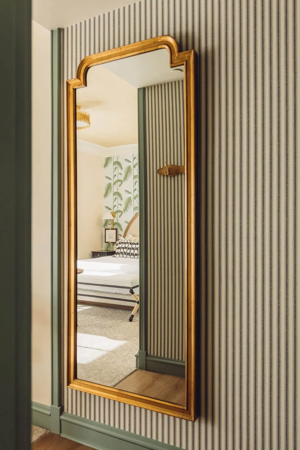 A mirror revealing a queen bed in a hotel room