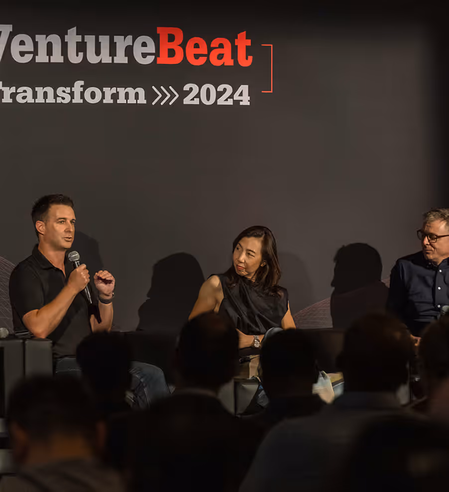 Three panelists sit on stage at a VentureBeat Transform 2024 event, with one man speaking into a microphone.