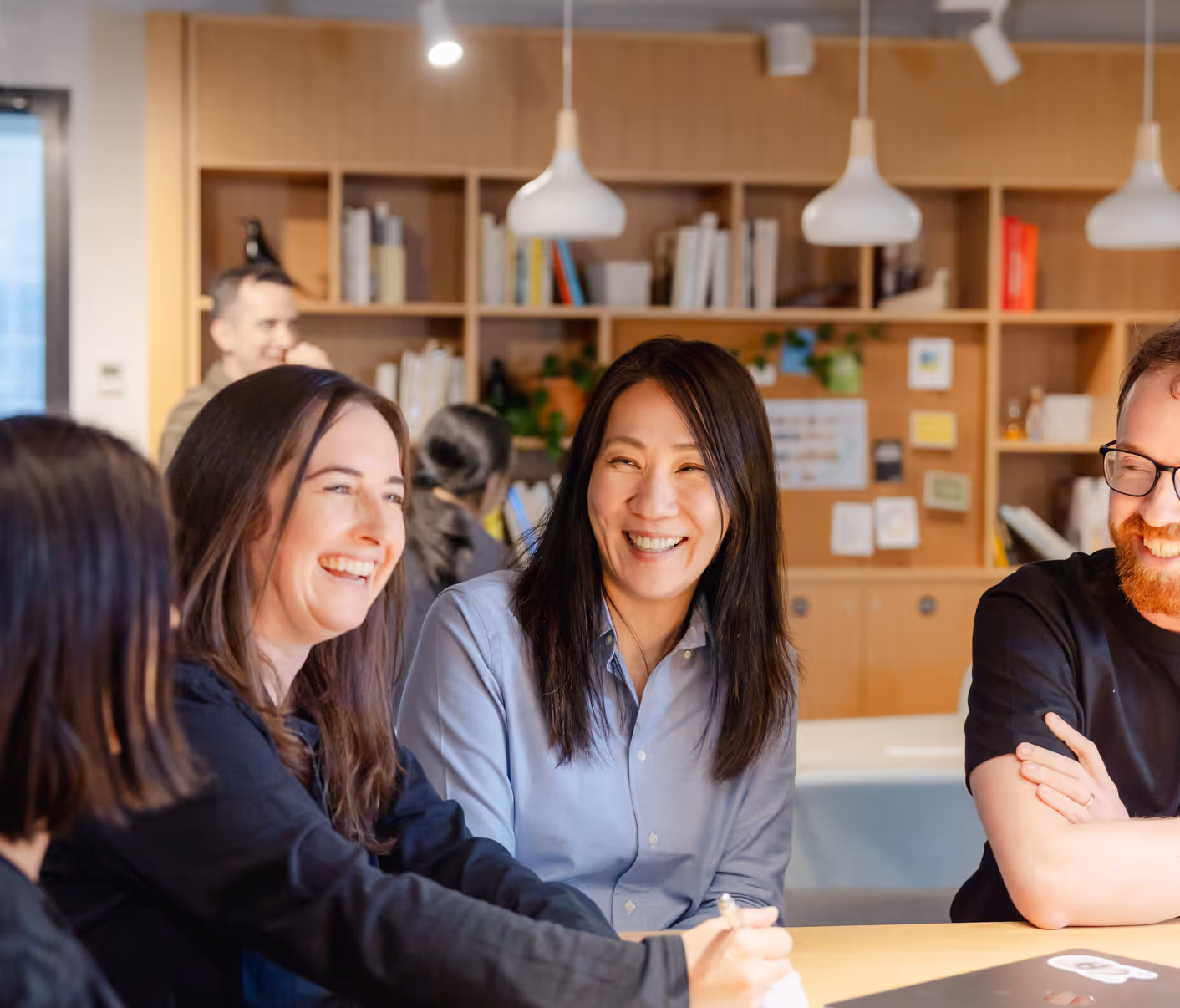 Four members of the UneeQ team laughing as they discuss an innovative digital human project.
