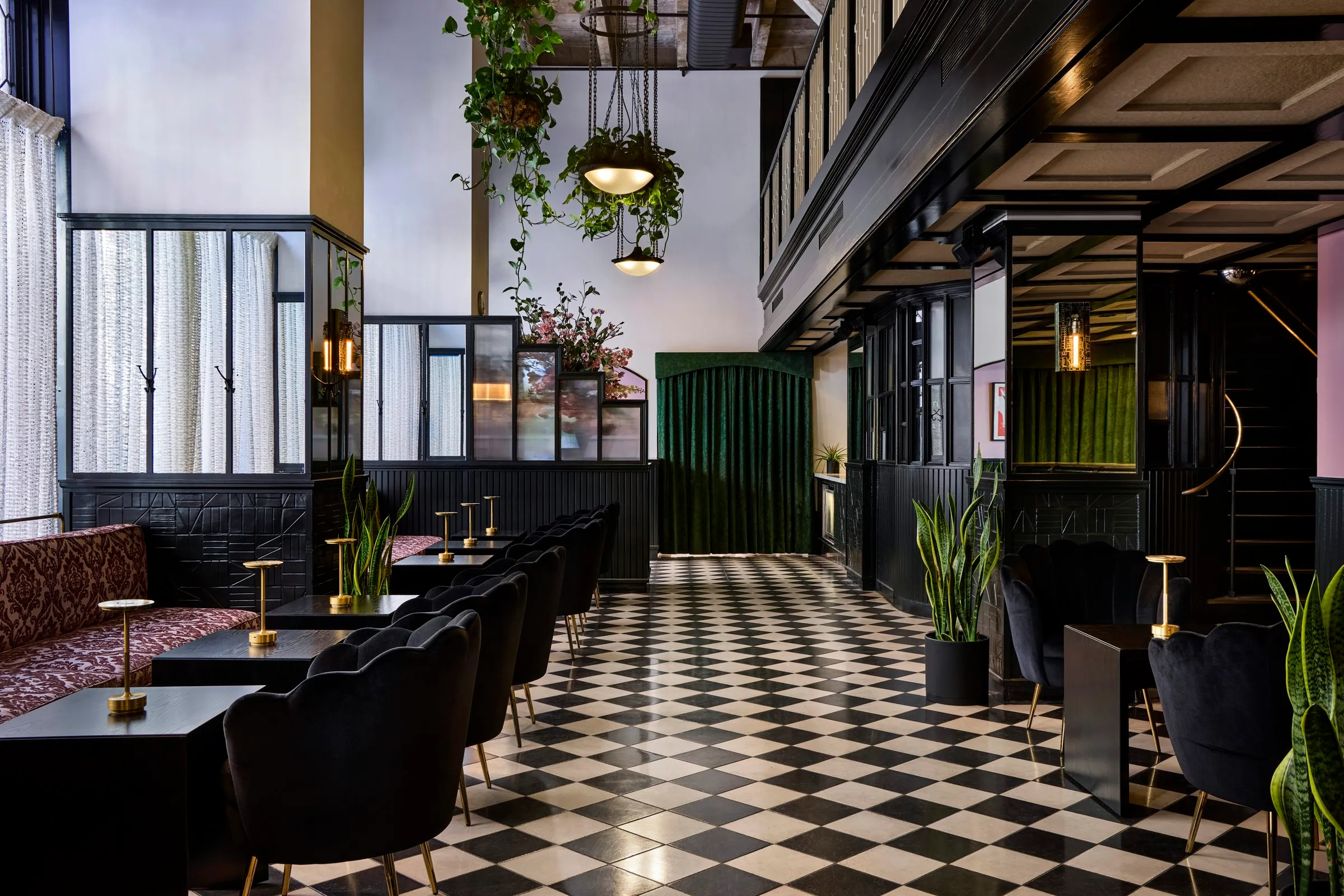Black scalloped chairs, potted plants and an arch hung with green velvet curtains at Mary at the Stile Hotel.