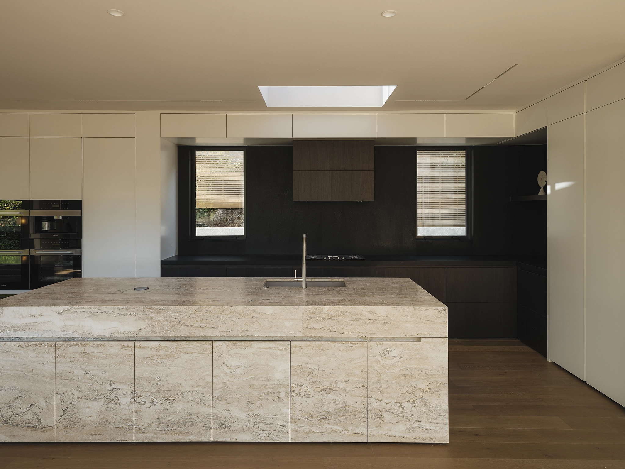Shinnoki Stardust Walnut timber veneer NZ rich in grain and colour alongside travertine, Codrington Residence