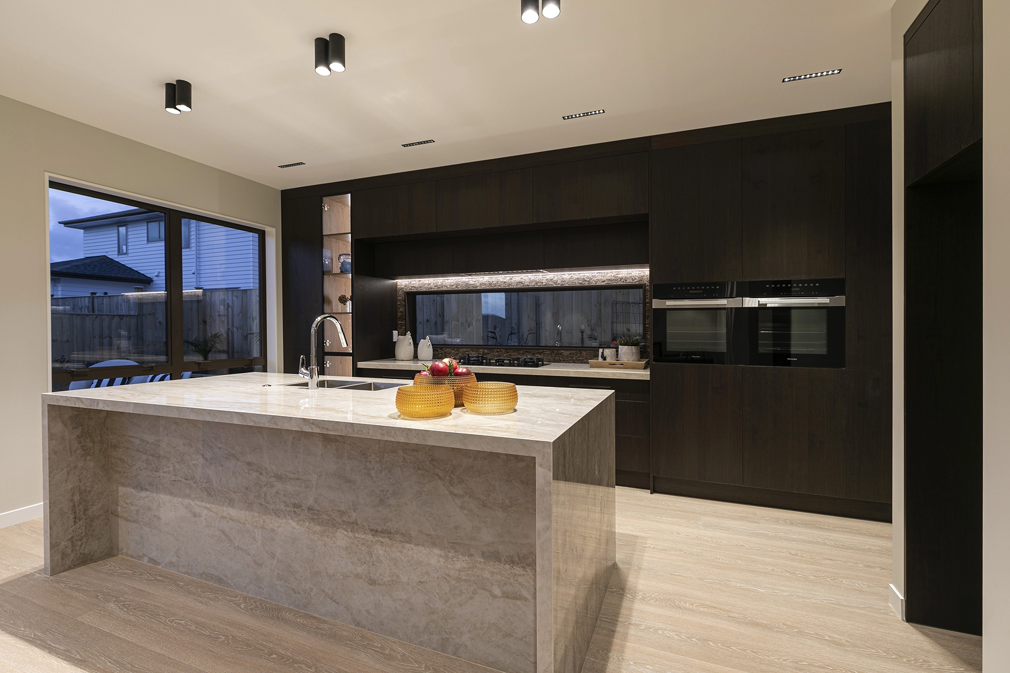 Dark timber joinery kitchen cabinetry with integrated cooking appliances, Pepeke Way, Auckland
