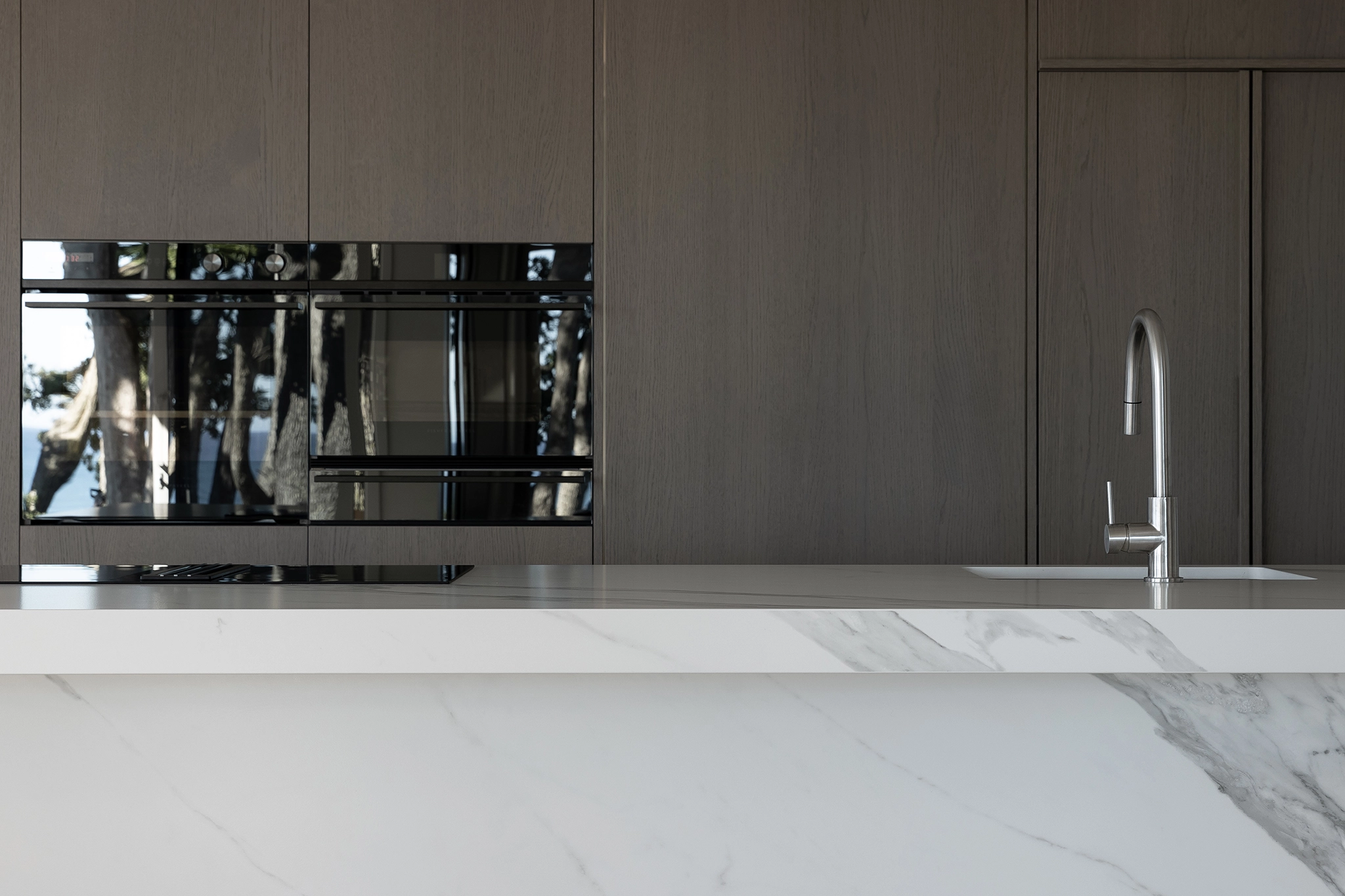 Prefinished timber veneer NZ cabinetry with integrated appliances in a coastal Oakura home