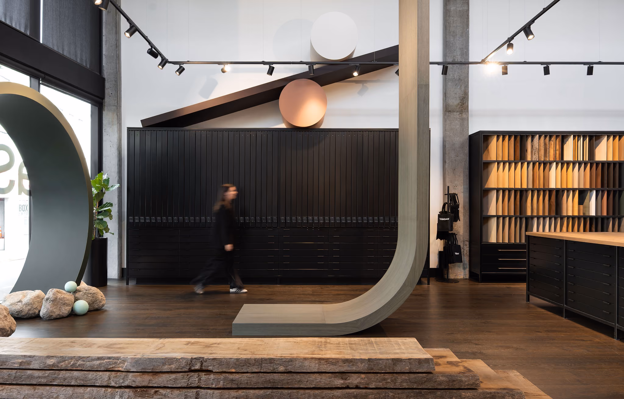 Modern showroom with wood flooring samples, black cabinets, and geometric wall decorations.