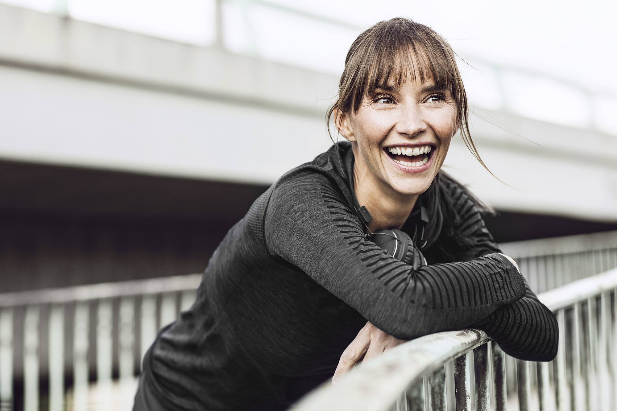 Woman smiling outdoors, leaning on a railing