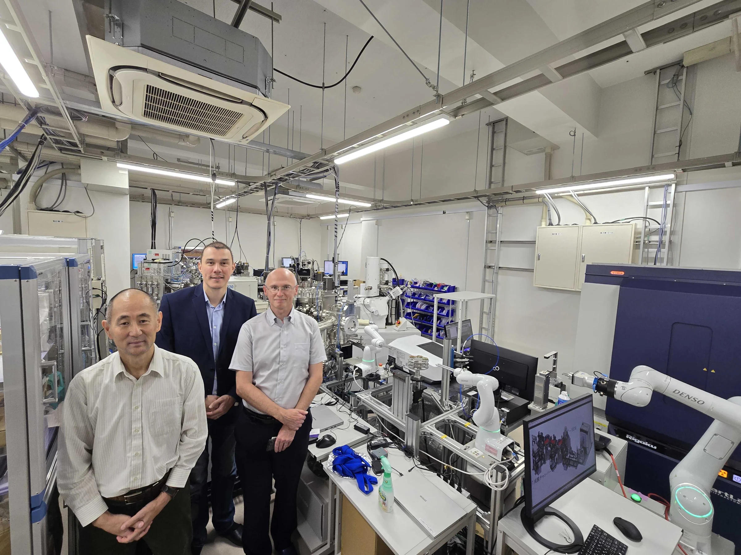 Mat3ra team members and a host standing in the lab among robotic arms and experimental equipment