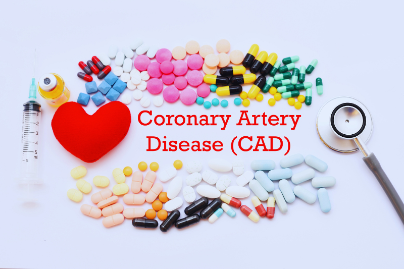 A red heart, a syringe, a stethoscope, and a variety of colorful pills are arranged on a white surface with the words "Coronary Artery Disease (CAD)" written in red text.