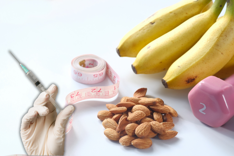 Bananas, almonds, a measuring tape, and a pink dumbbell on a white surface, suggesting a healthy lifestyle.