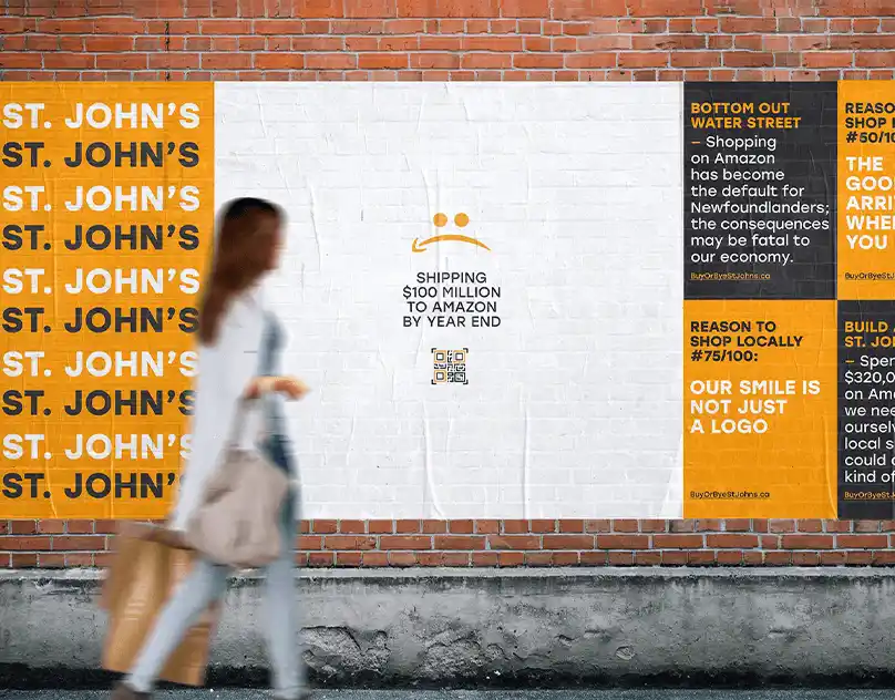 A campaign poster on a brick wall showing messages about local shopping in St. John’s and Amazon spending.