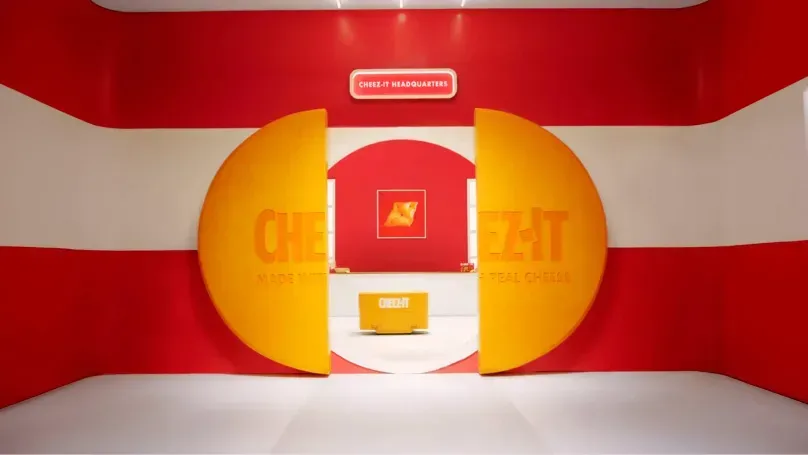 Красно-белая комната с гигантскими дверями в форме крекеров Cheez-It, ведущими в штаб-квартиру бренда, с центральной стойкой регистрации.