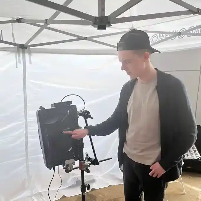 Андрей Реуцкий на съемочной площадке смотрит на монитор под навесом.