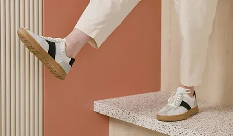 Close-up of Casca Avro x Volvo sneakers on terrazzo ledge, black stripe knit upper, gum sole, minimalist Scandinavian sustainable design.