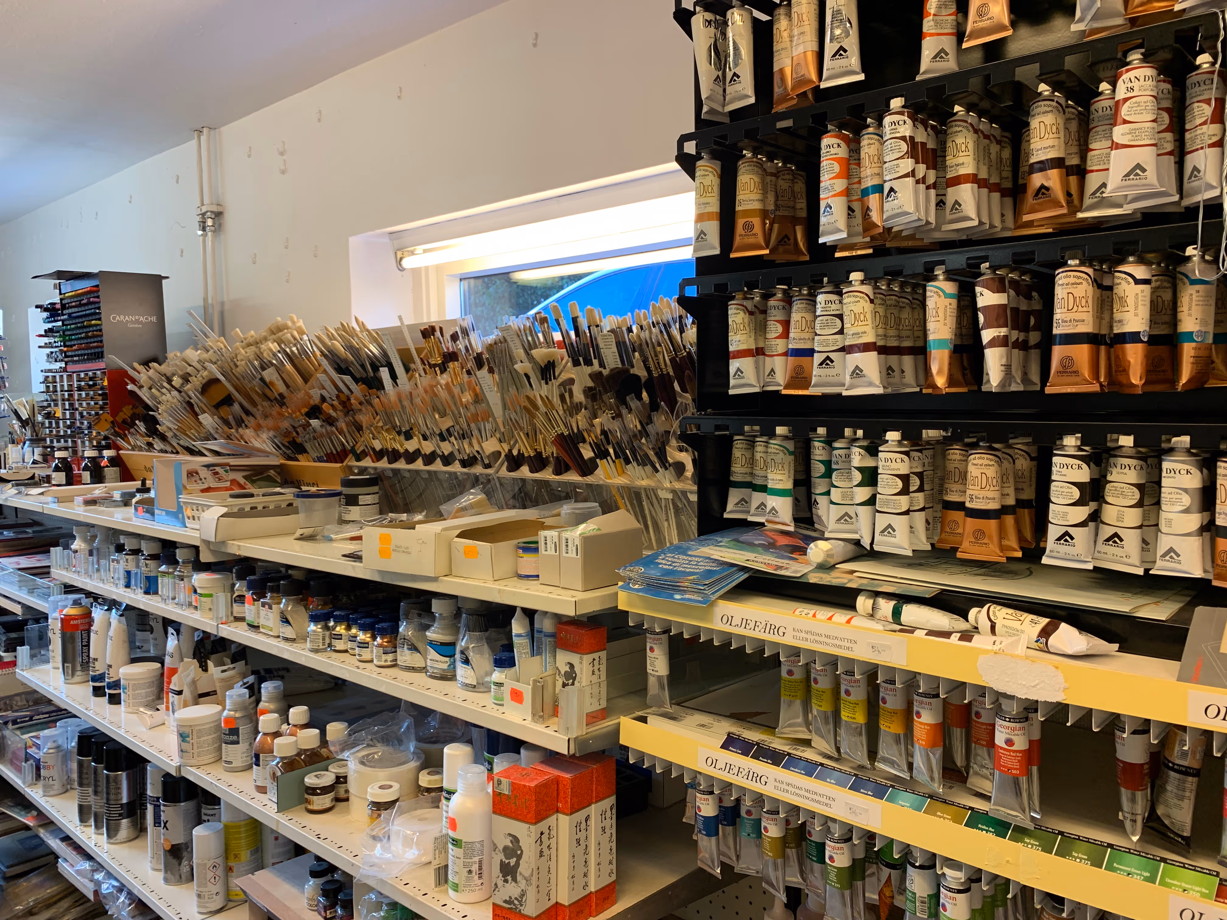 Hyllor som är fyllda med penslar, färger och andra målartillbehör