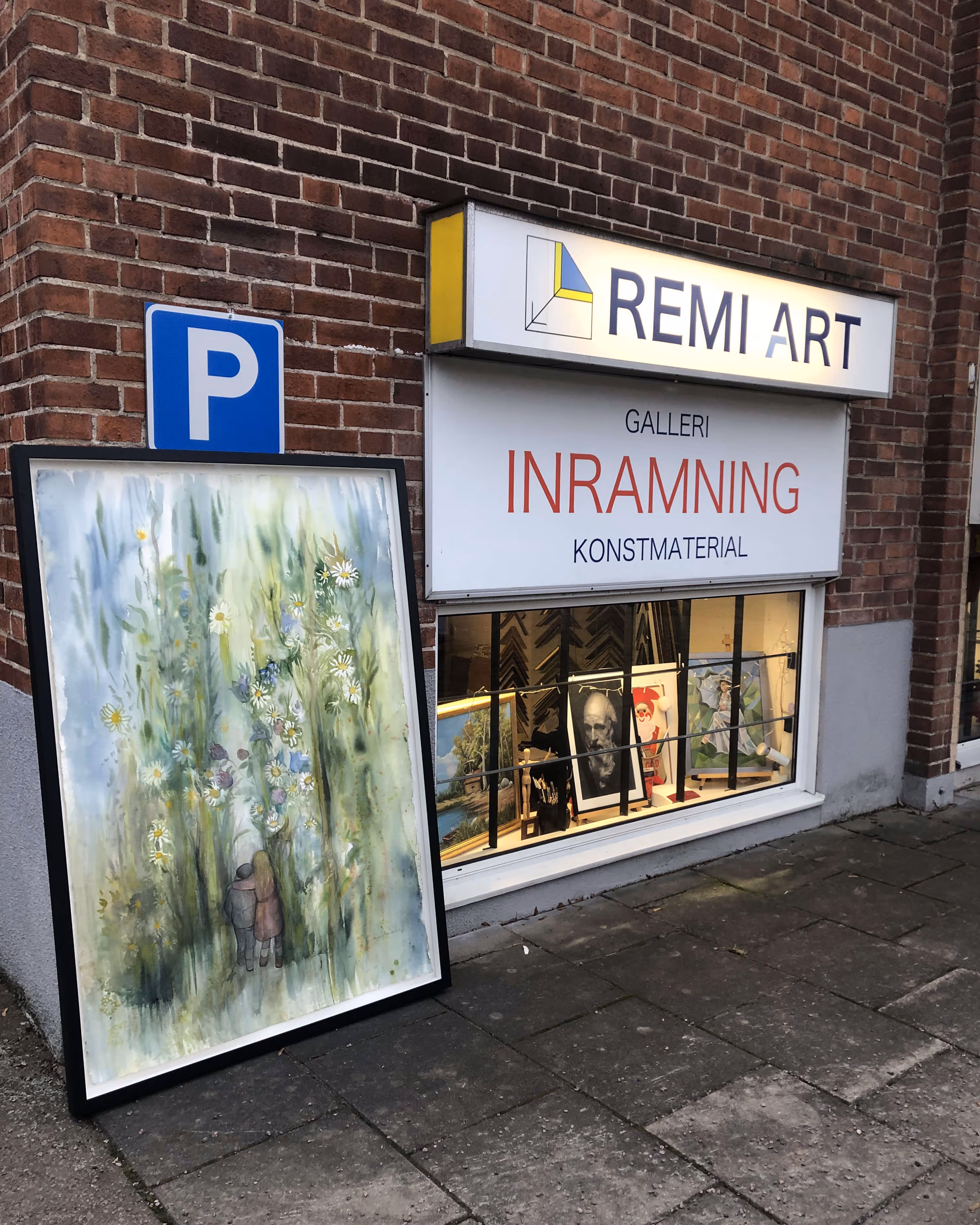 Remi Art-galleriets entré med ett stort inramat konstverk utanför. Skylten visar att butiken erbjuder galleri, inramning och konstmaterial.