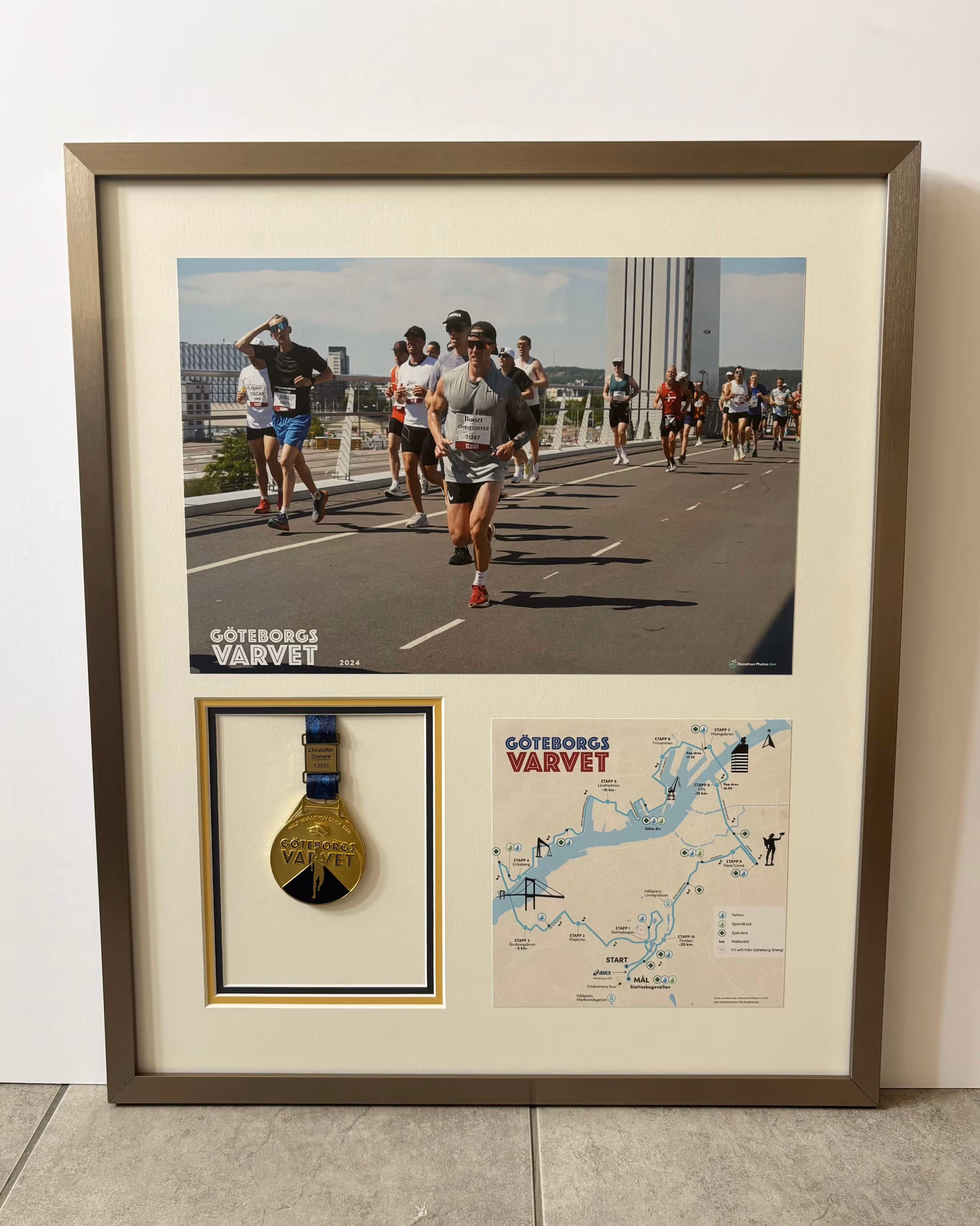 Inramat fotografi från Göteborgsvarvet där männisor springer på en asfalterad väg. Även en medalj samt en karta finns med i inramningen.