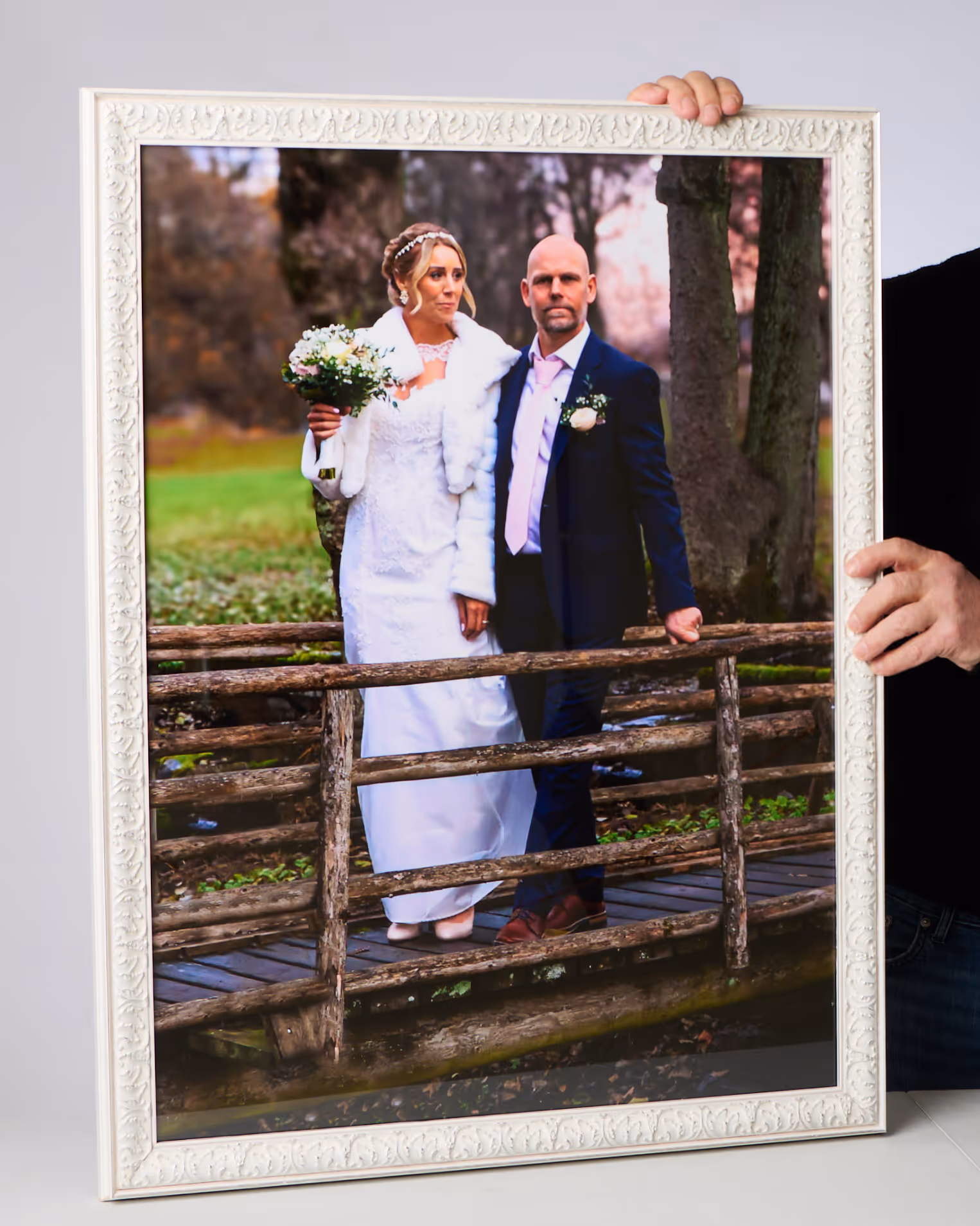 En människa håller upp en stor tavla föreställande ett brudpar