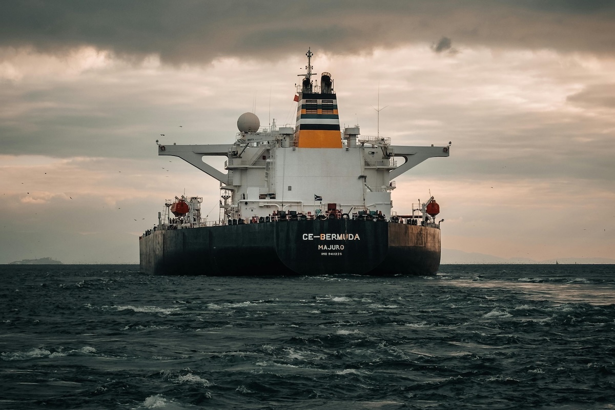 Shipping liner travels the seas in front of a beautiful sky carrying goods for international use.