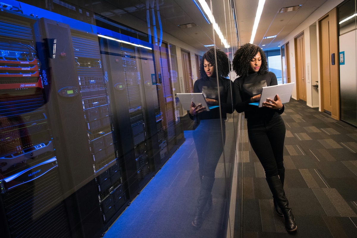 A woman works on cybersecurity in a server room of a secure office.
