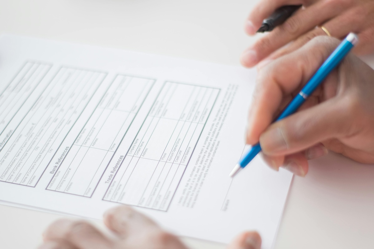 Two professionals execute licensing agreement paperwork at a desk in an office.