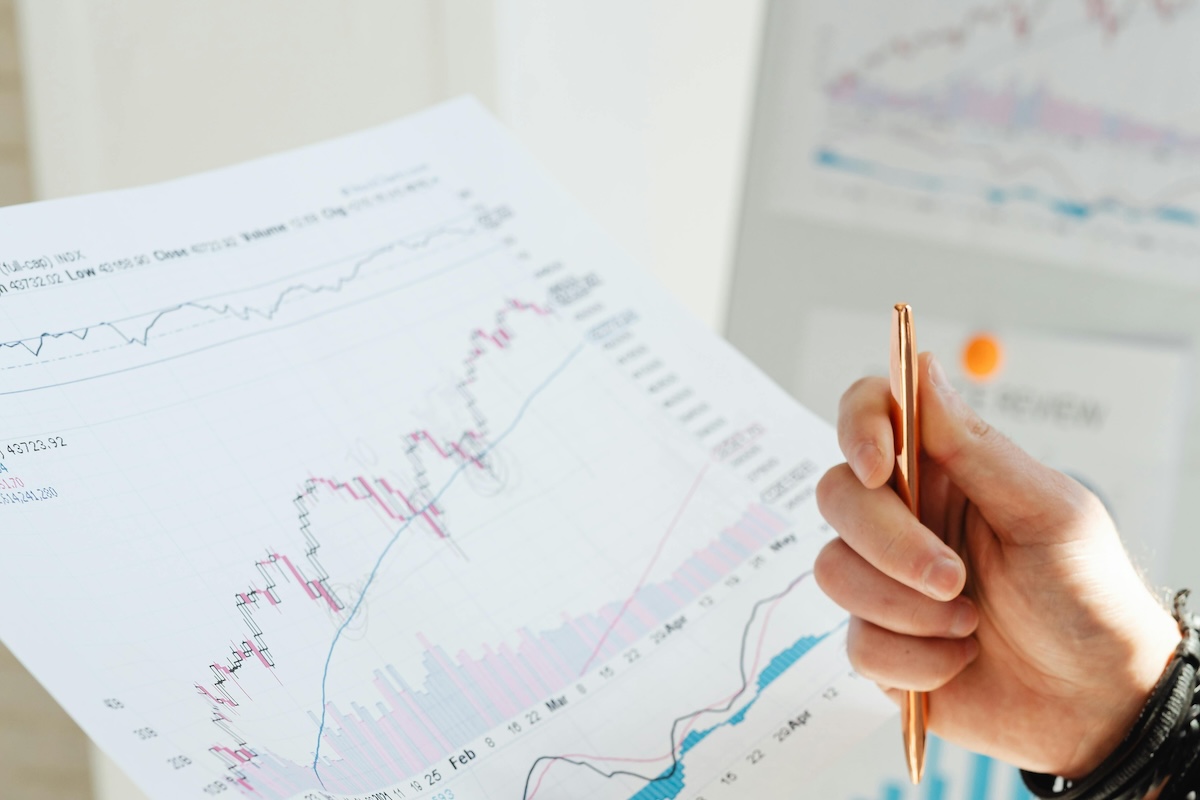 A person interprets the data with a pen in her hand while holding and reviewing graphs around her.