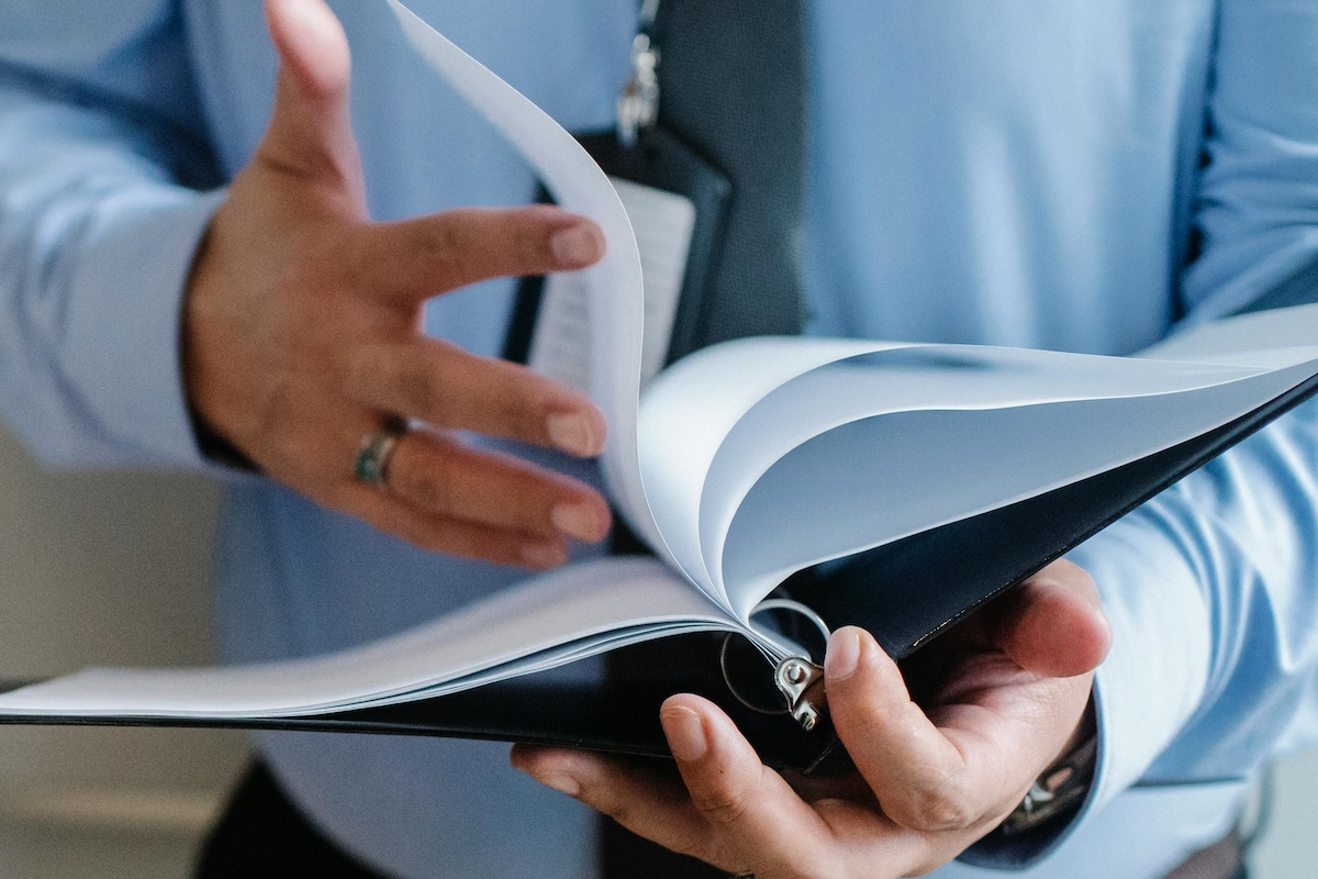 A business professional in a suit flips through documents indoors, emphasizing formal work settings.