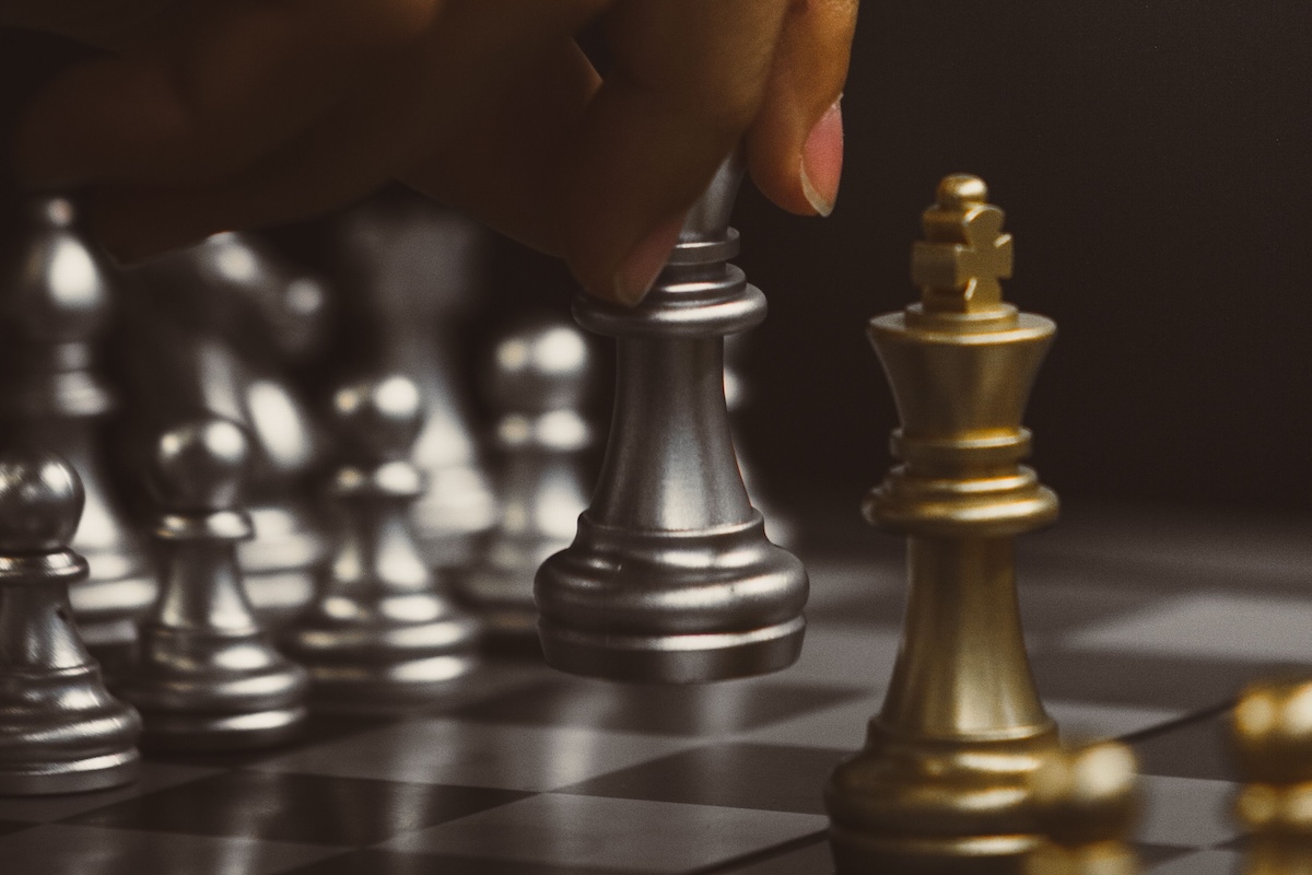 Close-up of a chess player making a move with metallic chess pieces, emphasizing strategy and focus.