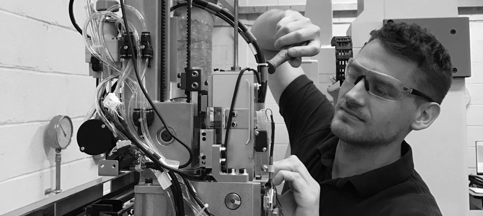 Technicien effectuant la maintenance d'une machine à mesurer tridimensionnelle (MMT) dans un laboratoire de métrologie.